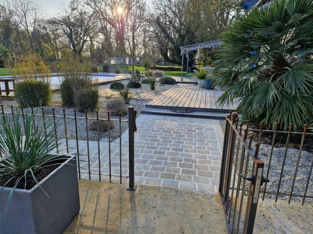 Jardin à Rennes avec allée en pavés de granit, terrasse bois et plantations paysagères